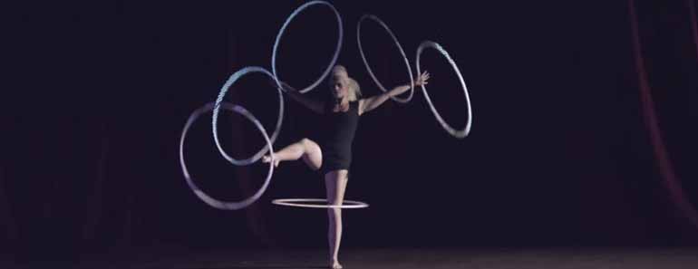 Photo of acrobatic dancer juggling multiple hula hoops.